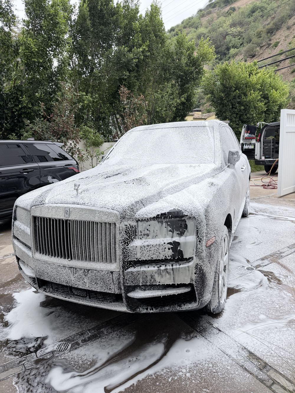Luxury SUV covered in snow foam during a hand wash
